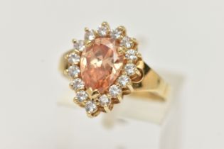 A DRESS RING, designed as a central pear shape peach cubic zirconia within a colourless circular