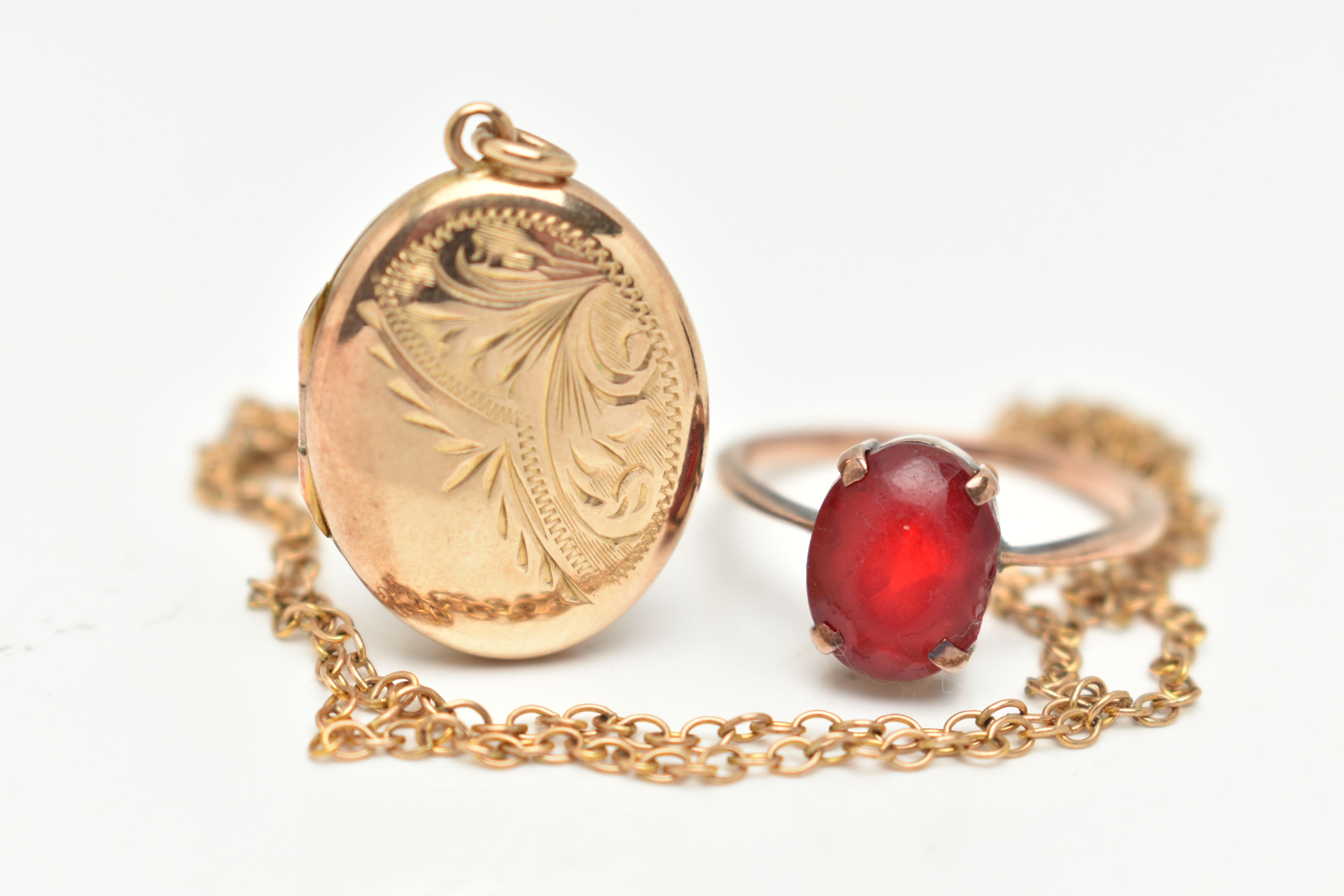 A YELLOW METAL RING, CHAIN AND OVAL LOCKET, the ring set with a rubbed and worn, oval cut red paste,