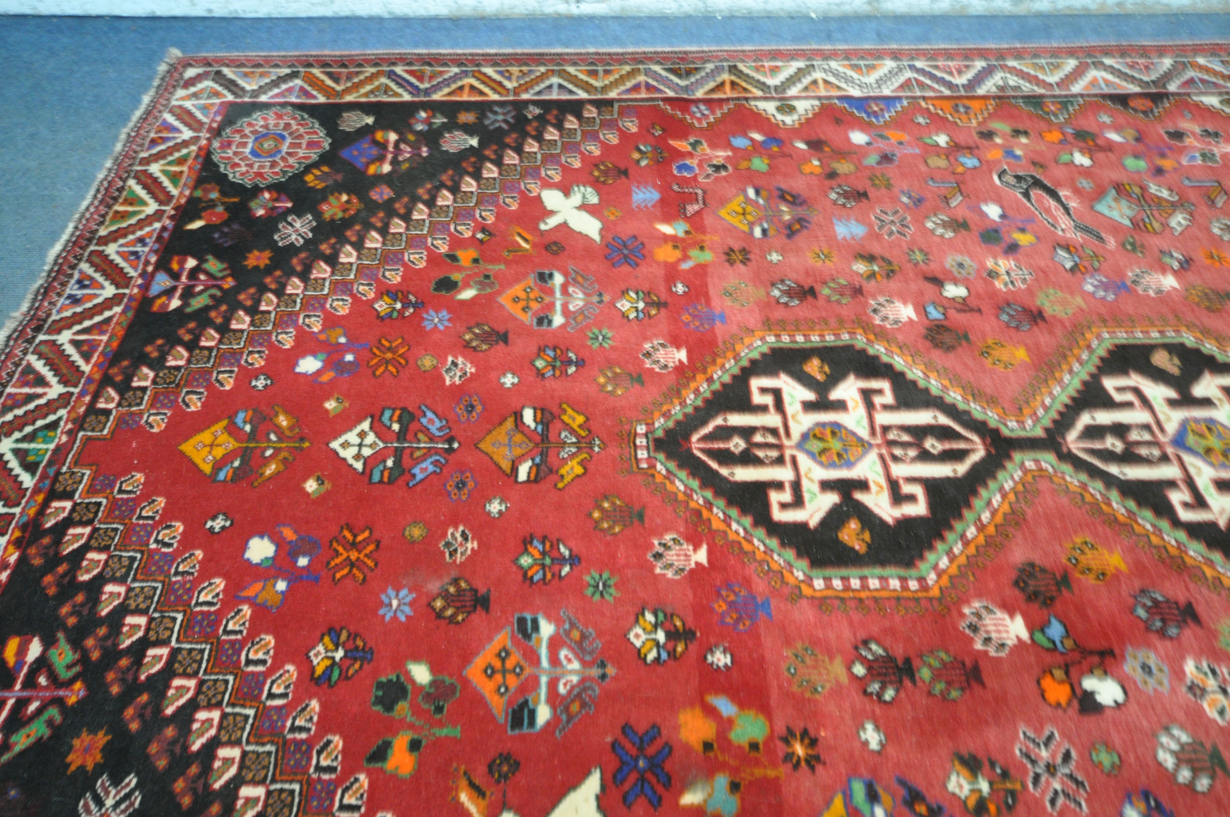 A WOOLLEN RED GROUND RUG, with a repeating pattern of birds, three central medallions, black - Image 4 of 6