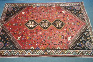 A WOOLLEN RED GROUND RUG, with a repeating pattern of birds, three central medallions, black