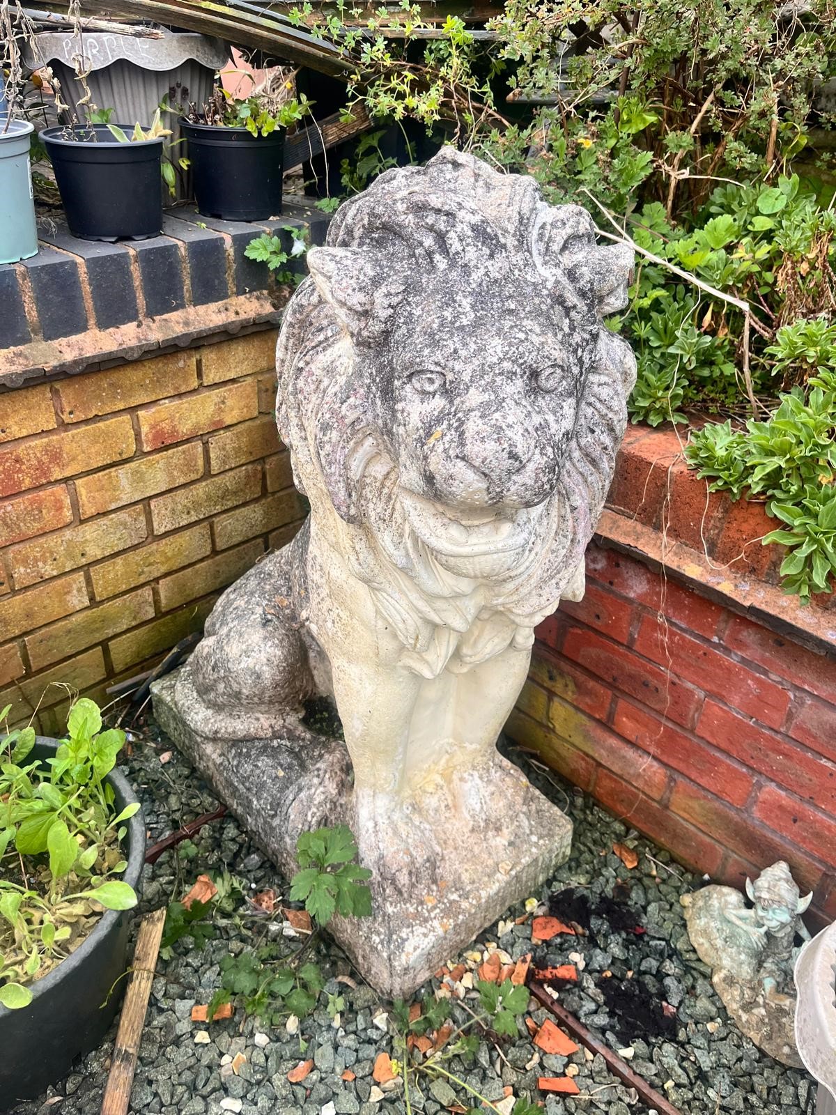 A PAIR OF WEATHERED COMPOSITE SEATED GARDEN LIONS, on a square plinth base, width 35cm x depth