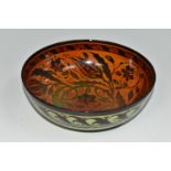 A PILKINGTON'S BOWL, decorated with flowers and foliage on a mid-green exterior and a red/orange