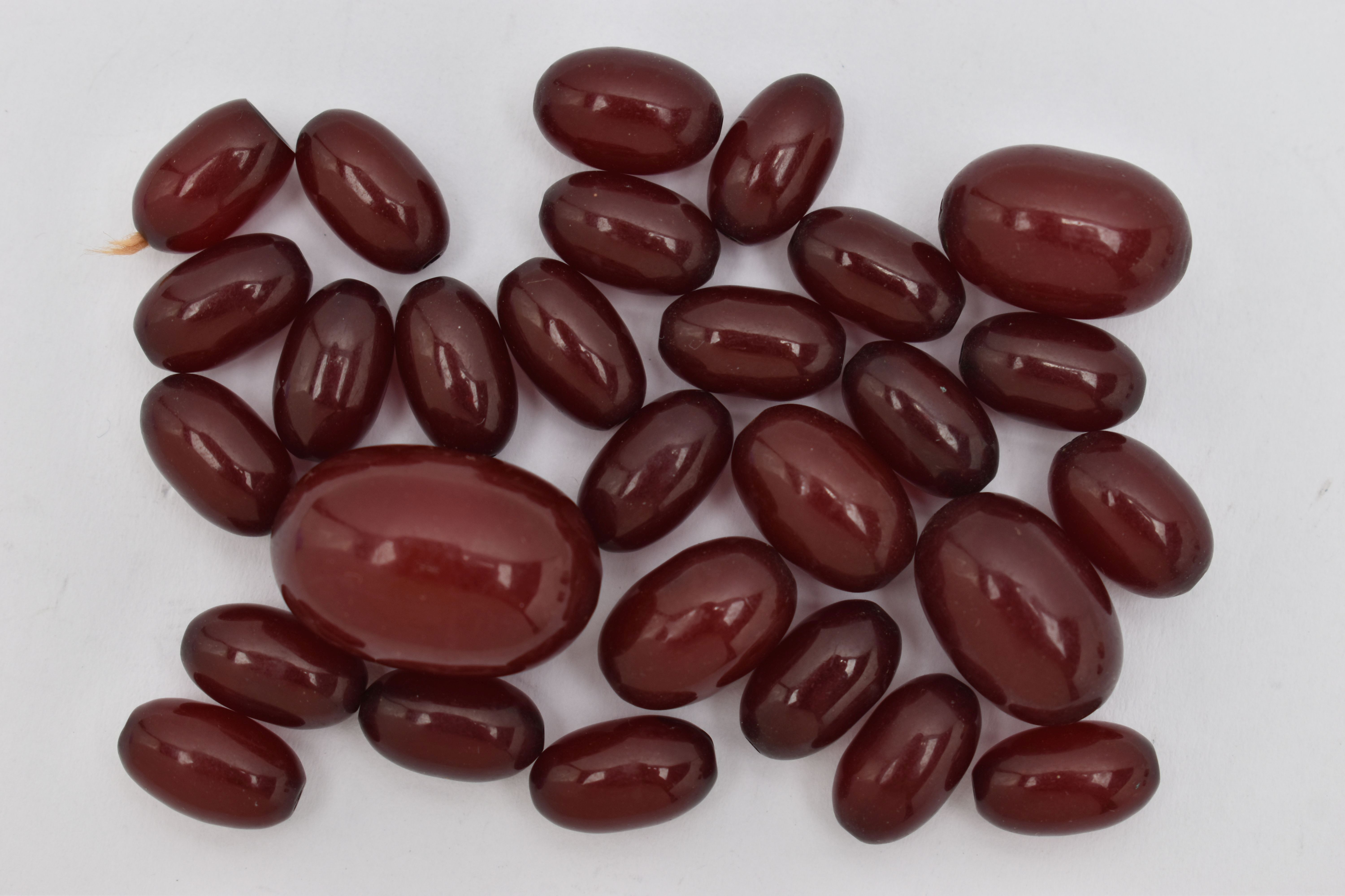 A SMALL QUANTITY OF CHERRY AMBER COLOUR BAKELITE BEADS, loose beads of an oval form, largest