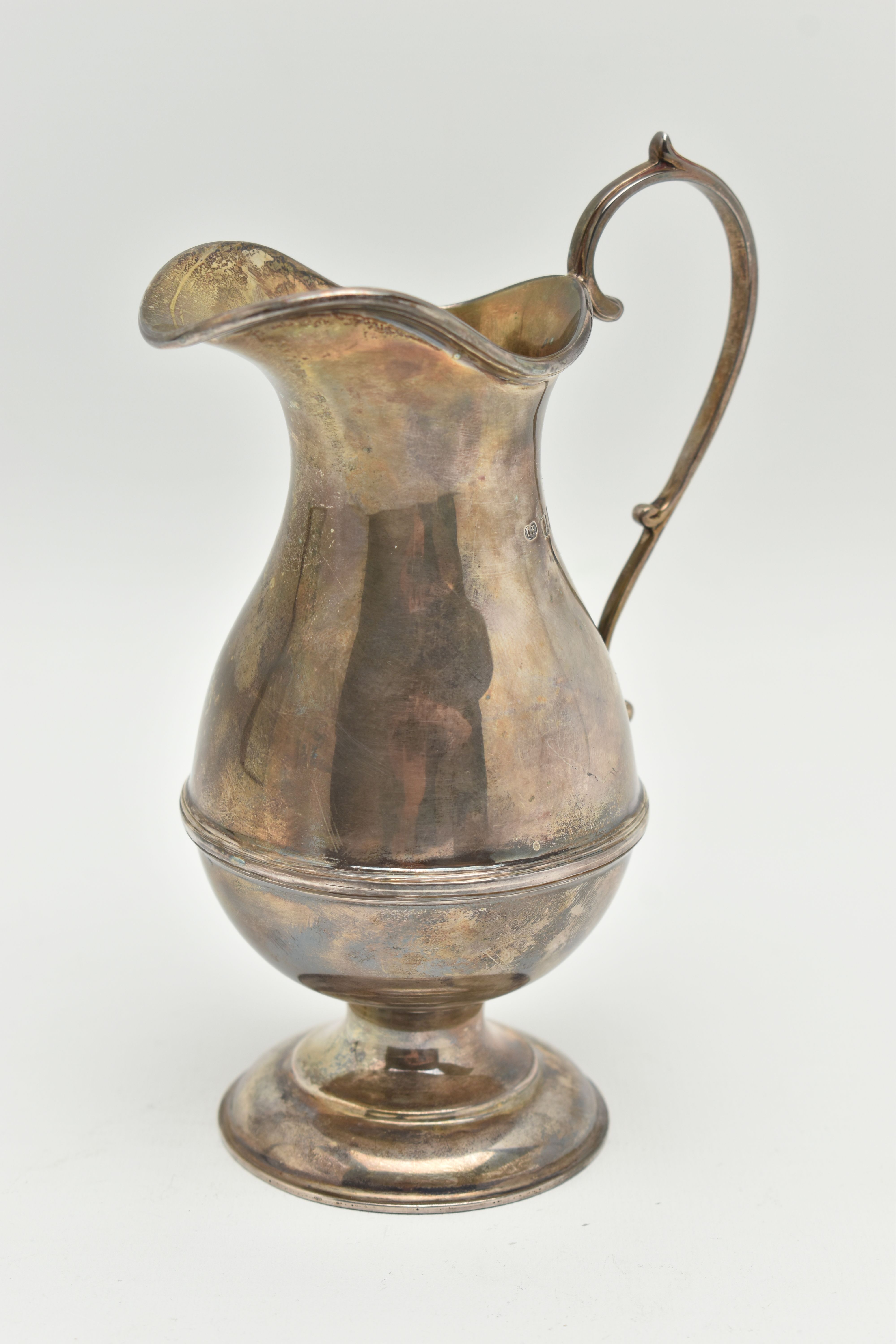 A GEORGE V SILVER CREAM JUG, a baluster form jug with a scrolling handle, approximate height