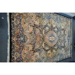 A LARGE WOOLLEN CREAM GROUND RUG, with a repeating foliate pattern, within a dark blue field, and