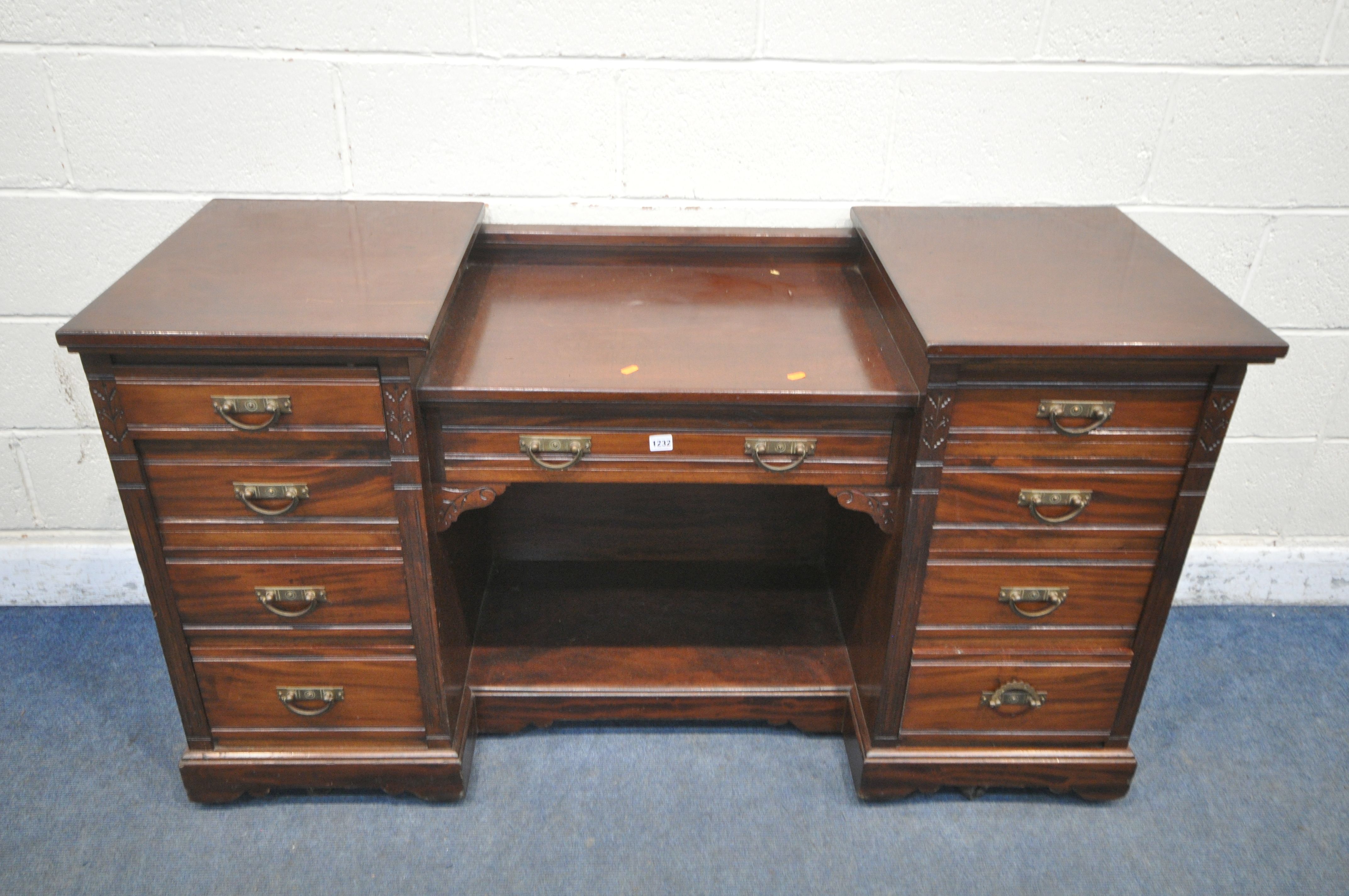 AN EDWARDIAN MAHOGANY DESK, fitted with nine drawers, on casters, width 152cm x depth 56cm x