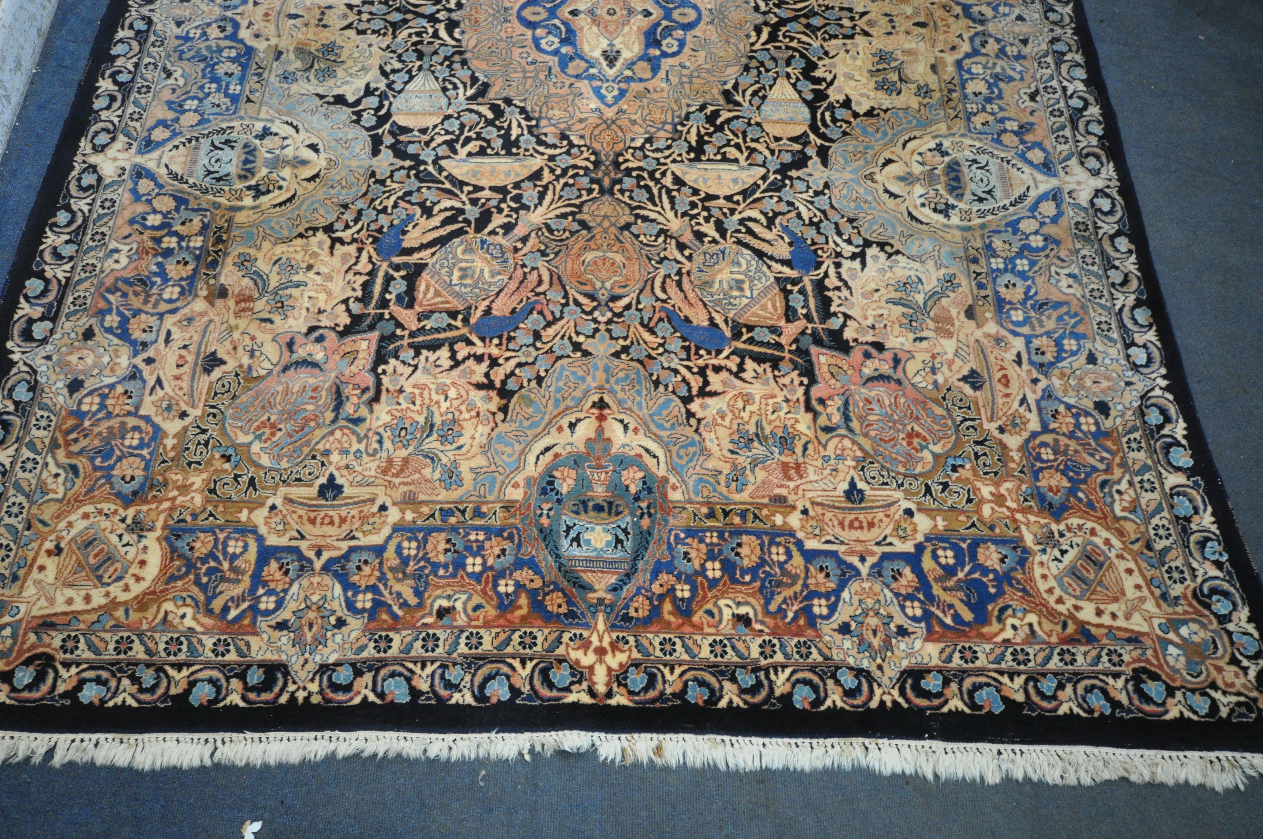 A LARGE WOOLLEN CREAM GROUND RUG, with a repeating foliate pattern, within a dark blue field, and - Image 2 of 6