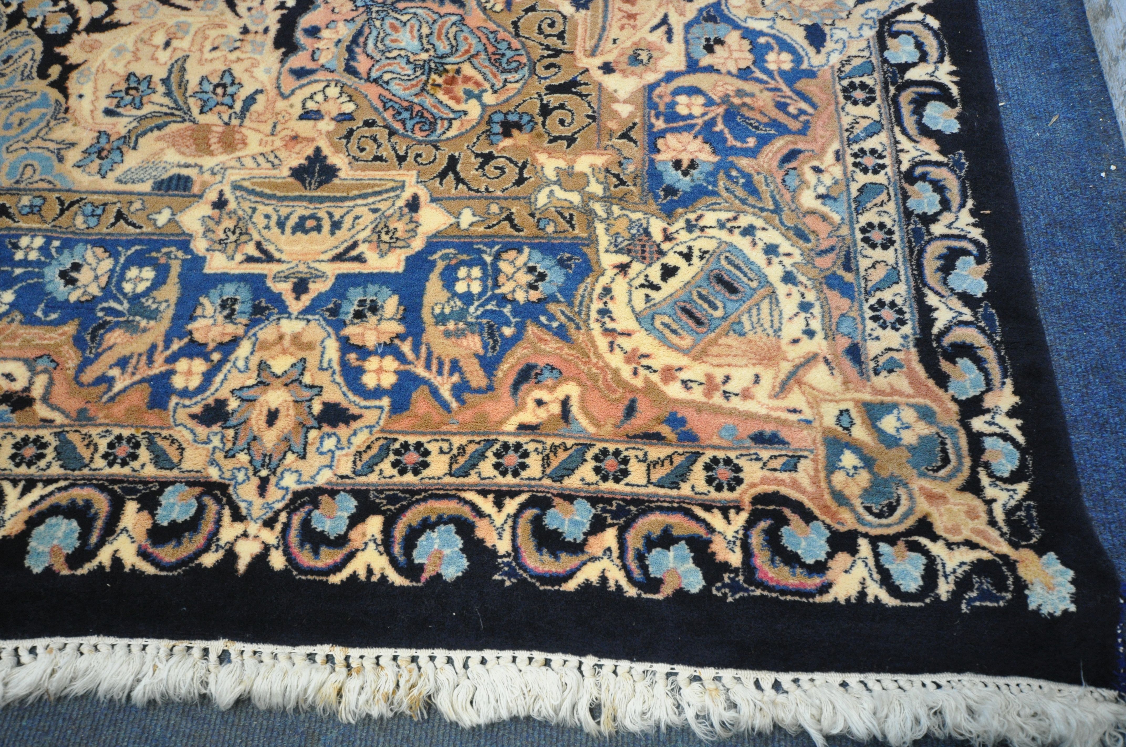 A LARGE WOOLLEN CREAM GROUND RUG, with a repeating foliate pattern, within a dark blue field, and - Image 4 of 6