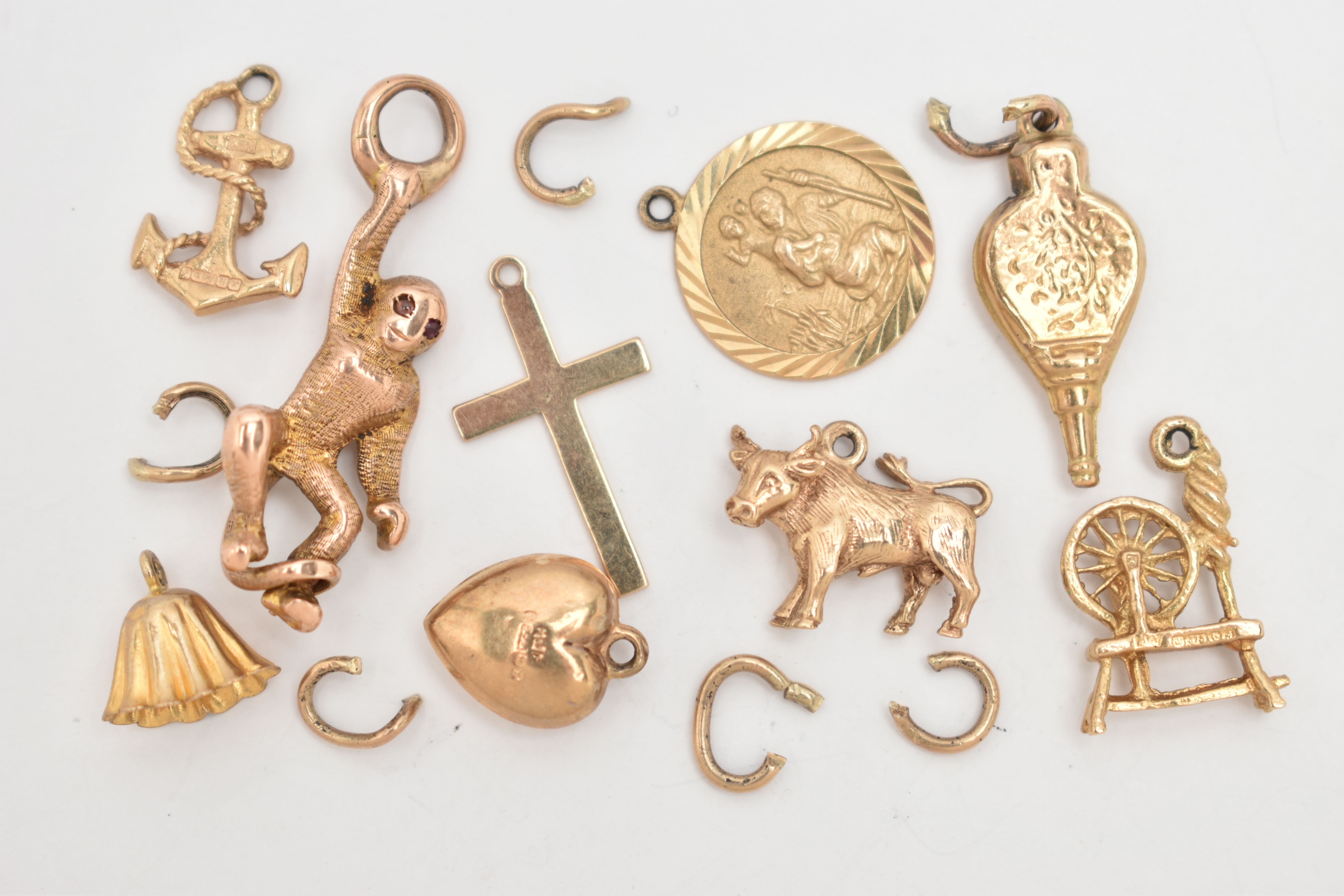 A SMALL BAG OF 9CT GOLD CHARMS, to include a bull, bell, bellowers, anchor, St. Christopher,
