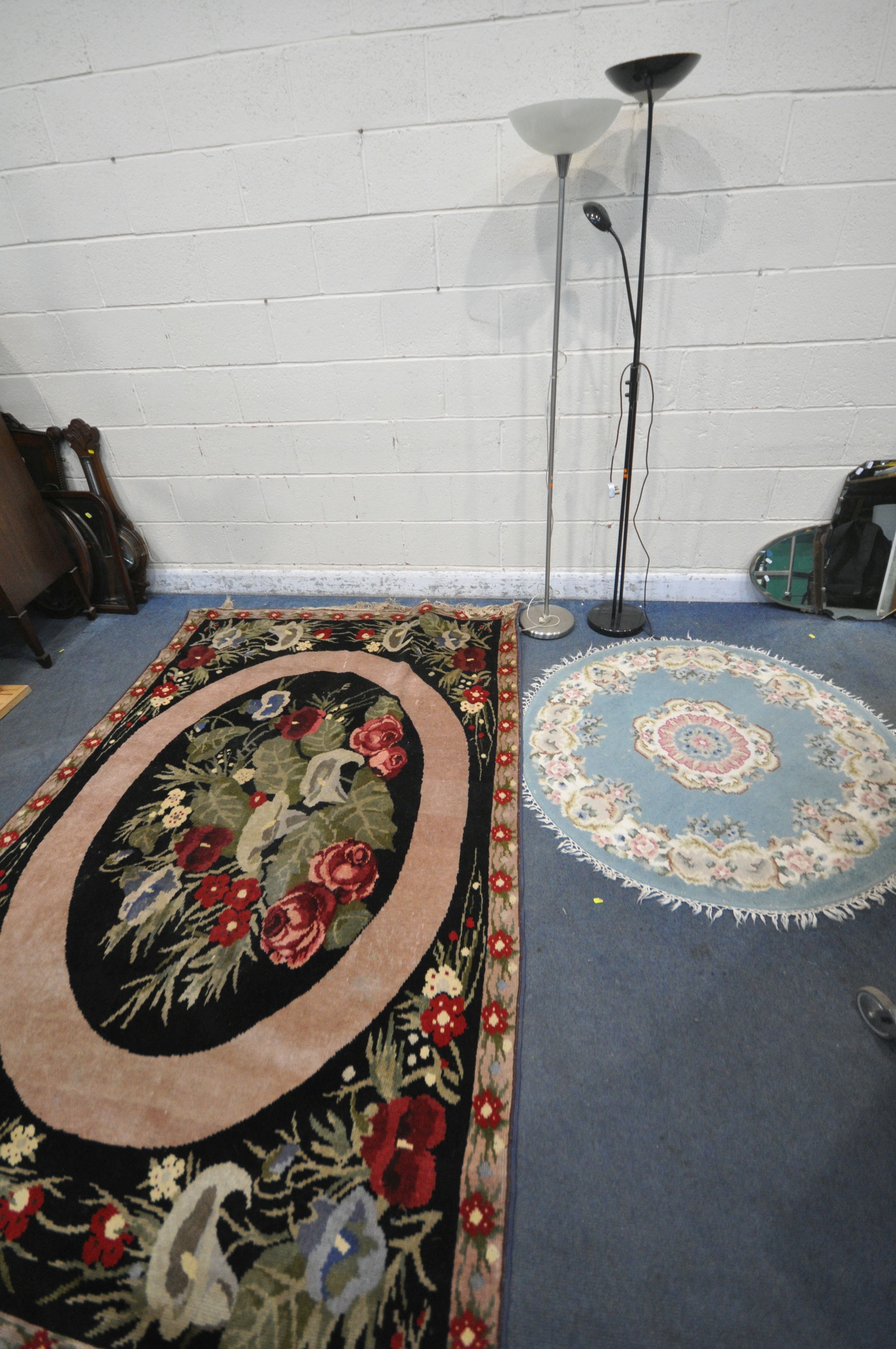 A WOOLLEN FLORAL RUG, on a black ground, 248cm x 168cm, along with a Chinese blue circular rug,