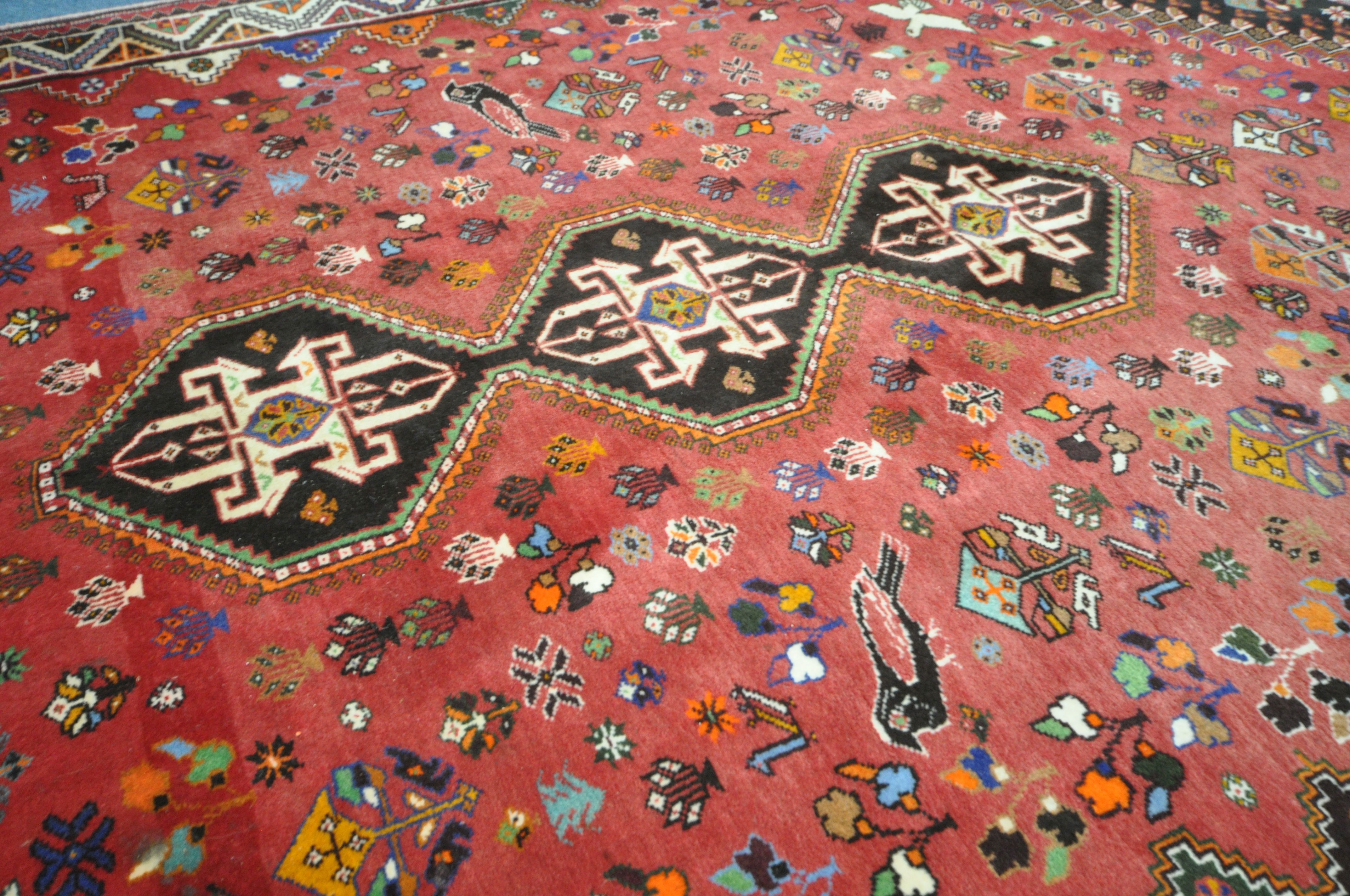 A WOOLLEN RED GROUND RUG, with a repeating pattern of birds, three central medallions, black - Image 3 of 6