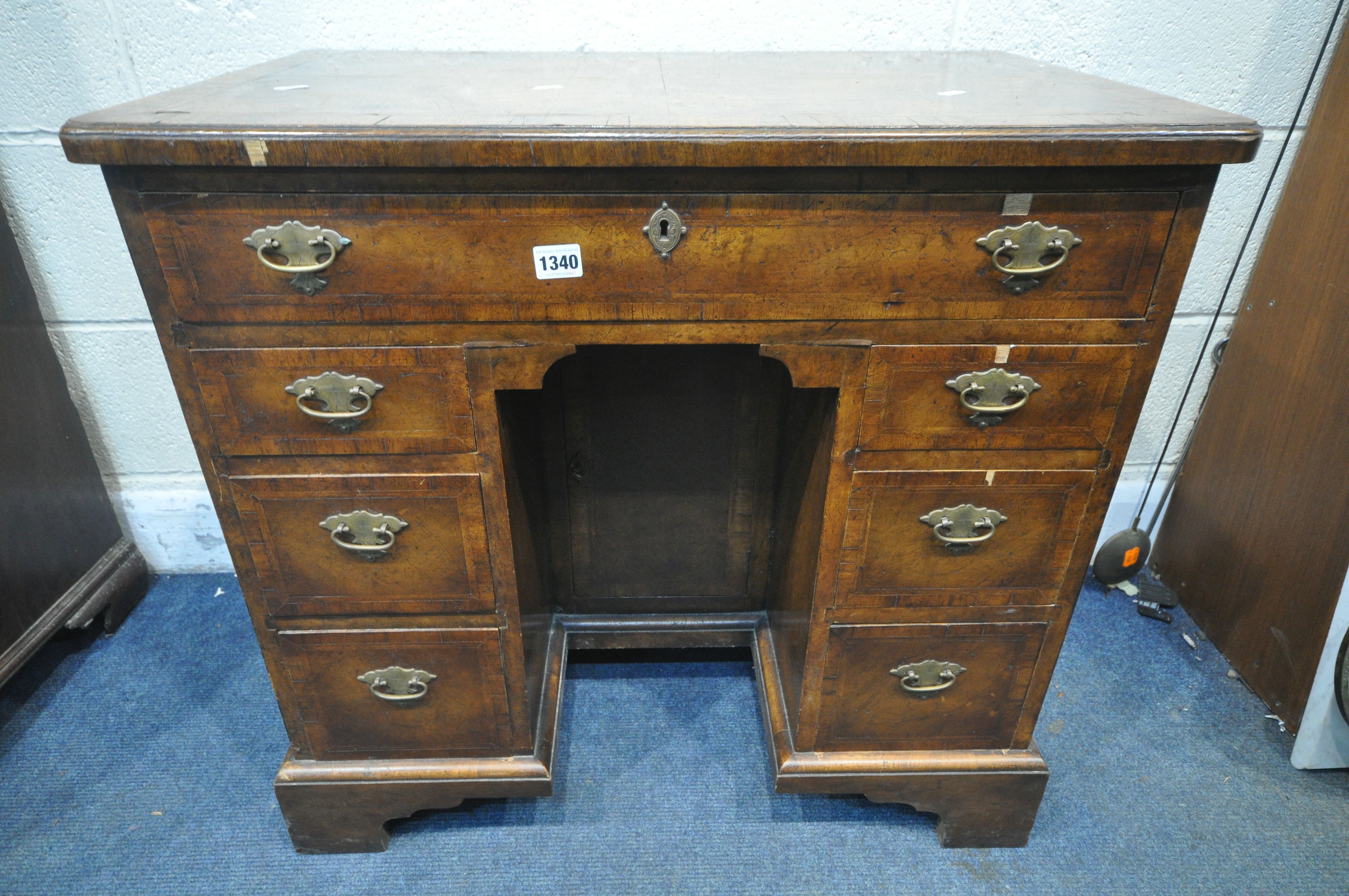 A REPRODUCTION GEORGIAN STYLE WALNUT KNEE HOLE DESK, the quarter veneer top, over an arrangement