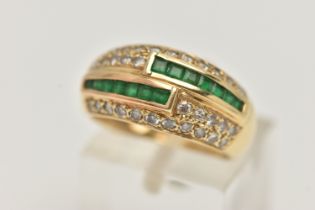 A YELLOW METAL EMERALD AND DIAMOND RING, a domed ring, channel set with square cut emeralds and pave