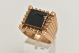 A LARGE YELLOW METAL GENTS RING, square form ring inlay set with onyx, approximate width 19mm,