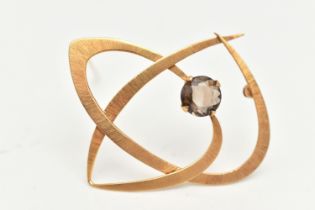 A YELLOW METAL ABSTRACT BROOCH, principally set with a circular cut smoky quartz, textured detail,