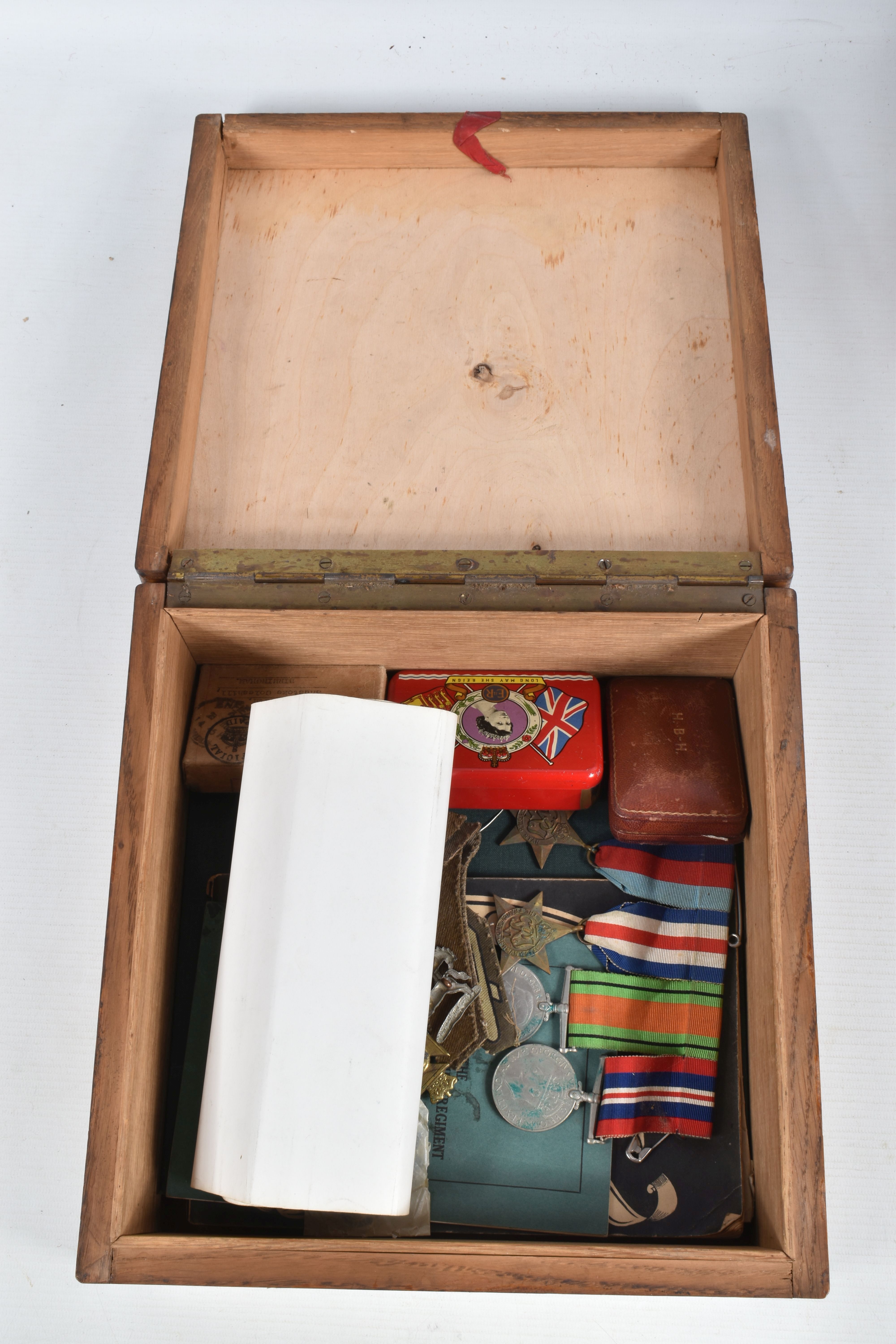 A WOODEN BOX CONTAINING TWO SETS OF WWII MEDALS, cap badges, formation patches and other military