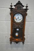 A LATE 19TH / EARLY 20TH CENTURY WALNUT WALL CLOCK, with an arched crest, flanked by twin finials,