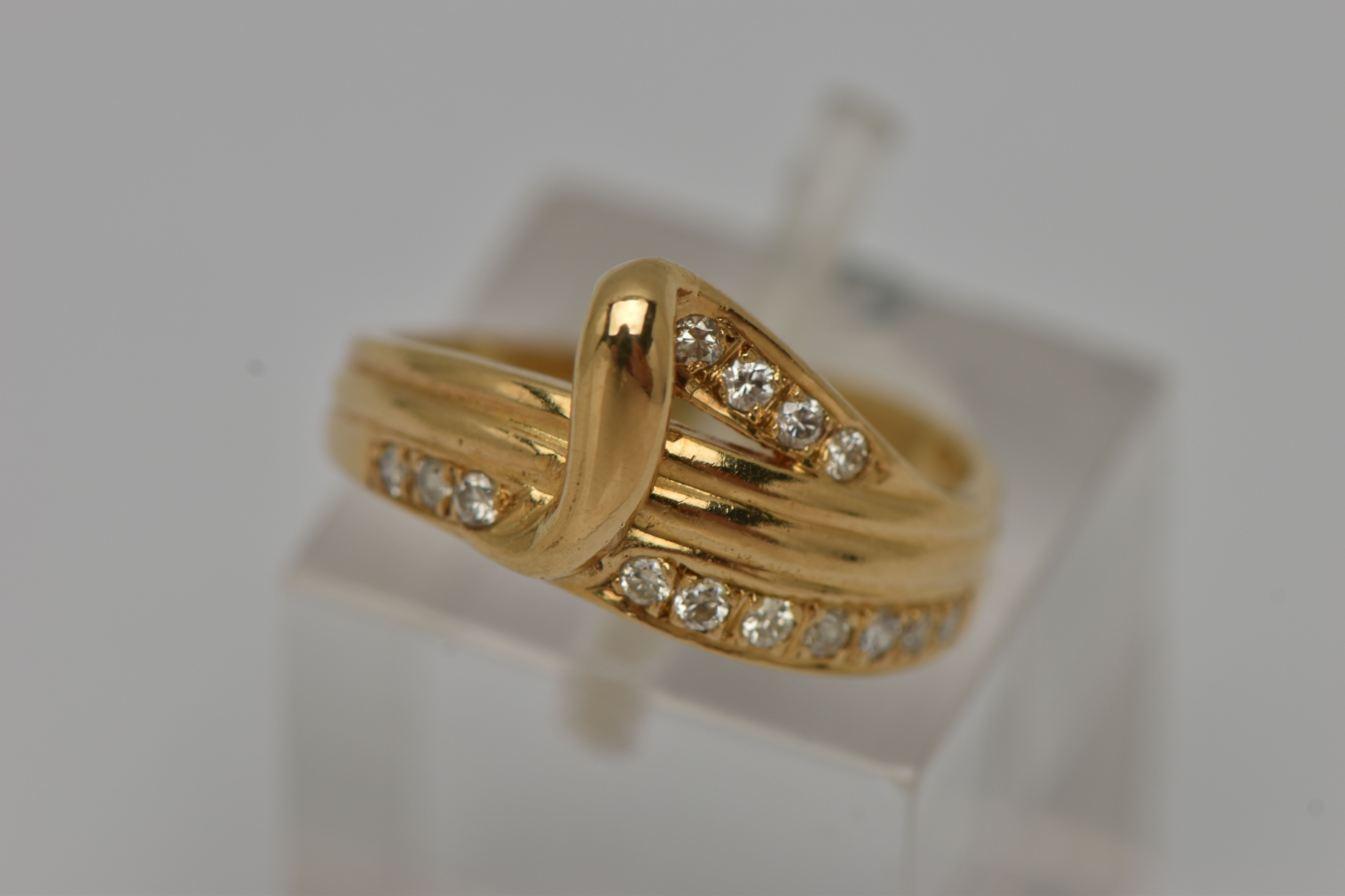 A YELLOW METAL DIAMOND SET RING, abstract band ring, grain set with fourteen round brilliant cut