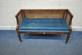 A LATE 20TH CENTURY WINDOW SEAT, with cane back and sides, blue upholstered seat, raised on square