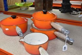 FOUR LE CREUSET CAST IRON SAUCEPANS, in orange enamel with pouring lips and wooden handles,