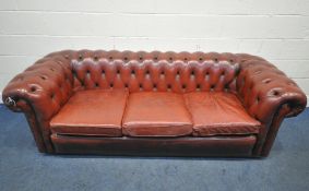 AN OXBLOOD LEATHER CHESTERFIELD THREE SEATER SOFA, with buttoned back and armrests, length 230cm x