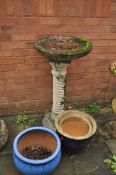 A WEATHERED RECONSTITUTED STONE BIRD BATH, with a spiral base height 92cm and three glazed plant