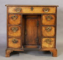 A George II walnut kneehole desk, second quarter 18th century, with an arrangement of seven drawe...