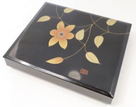 A Japanese black lacquer rectangular box and cover, 20th century, painted to the cover in gilt wi...