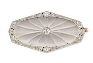 An Art Deco, rock crystal and diamond brooch, the sloped oval rock crystal panel with carved rays...