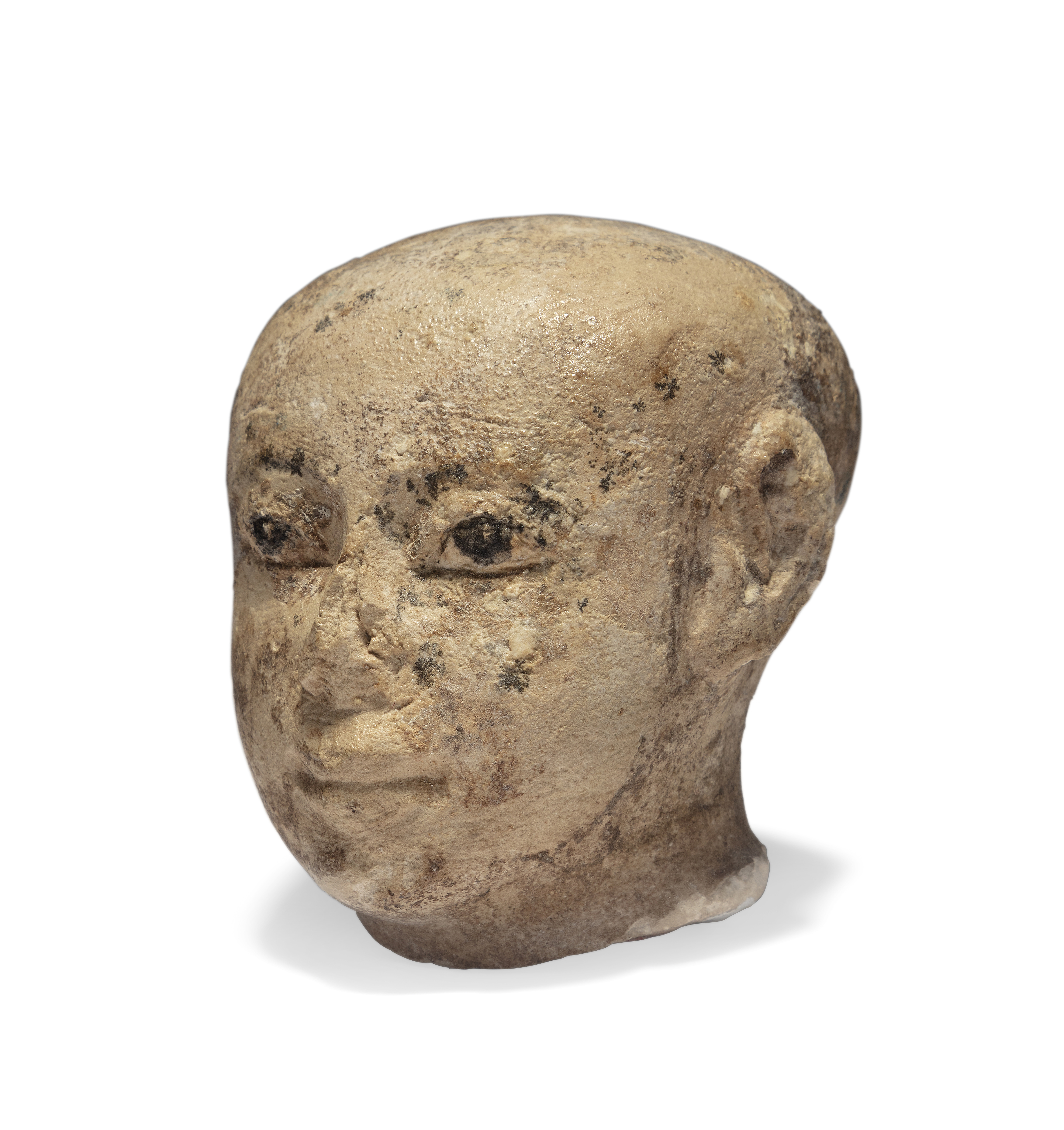 An Egyptian limestone male head with black painted pupils, probably Middle Kingdom, with traces...