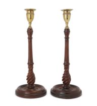 A pair of George III style turned mahogany candlesticks, 20th century, the brass sconces above fl...