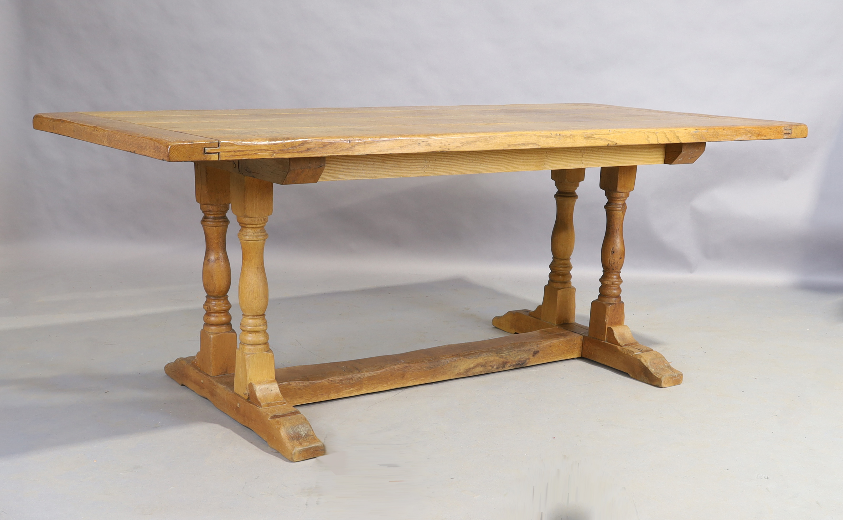 An English elm refectory table, late 19th/early 20th century, the plank top on turned legs to pla...