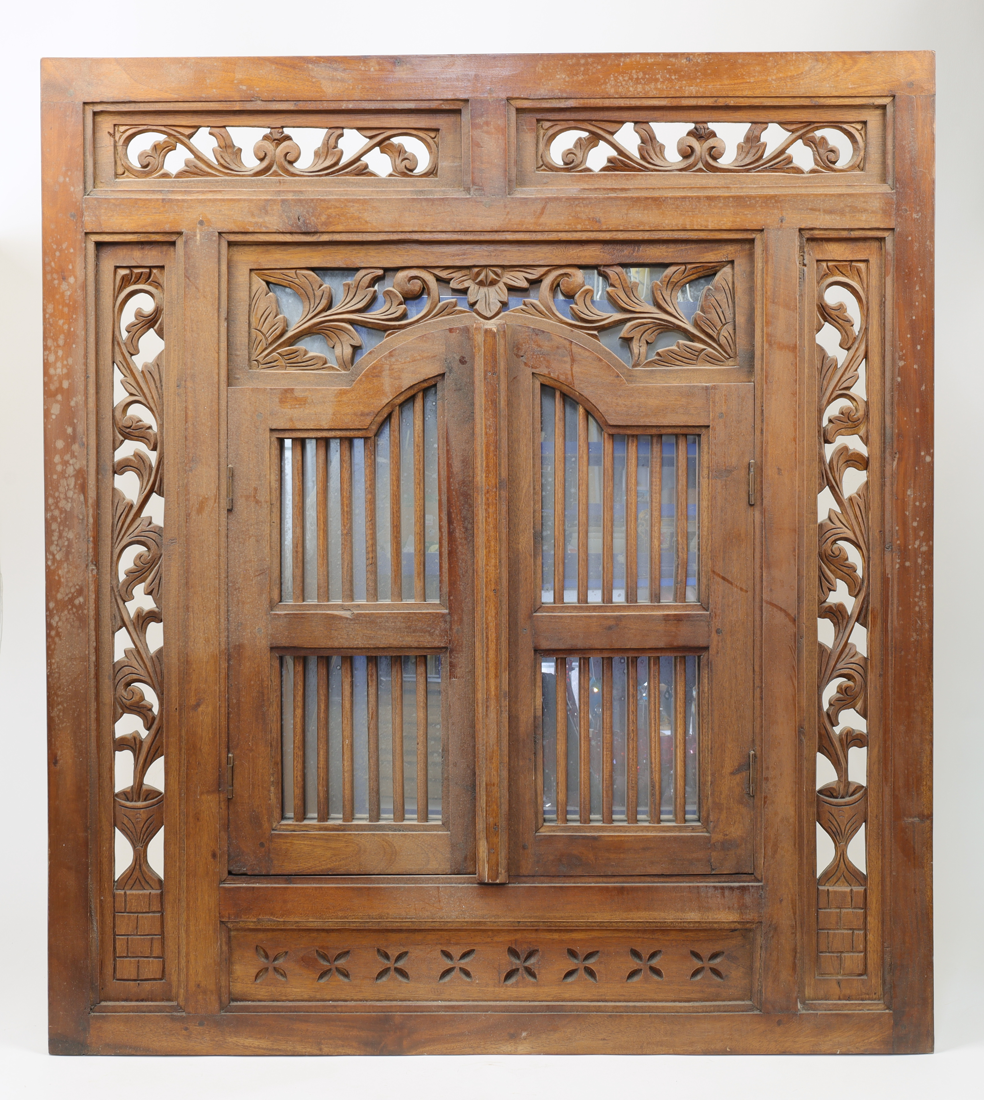 An Indonesian carved teak window shutter converted to a concealed mirror, 20th century, the hinge...