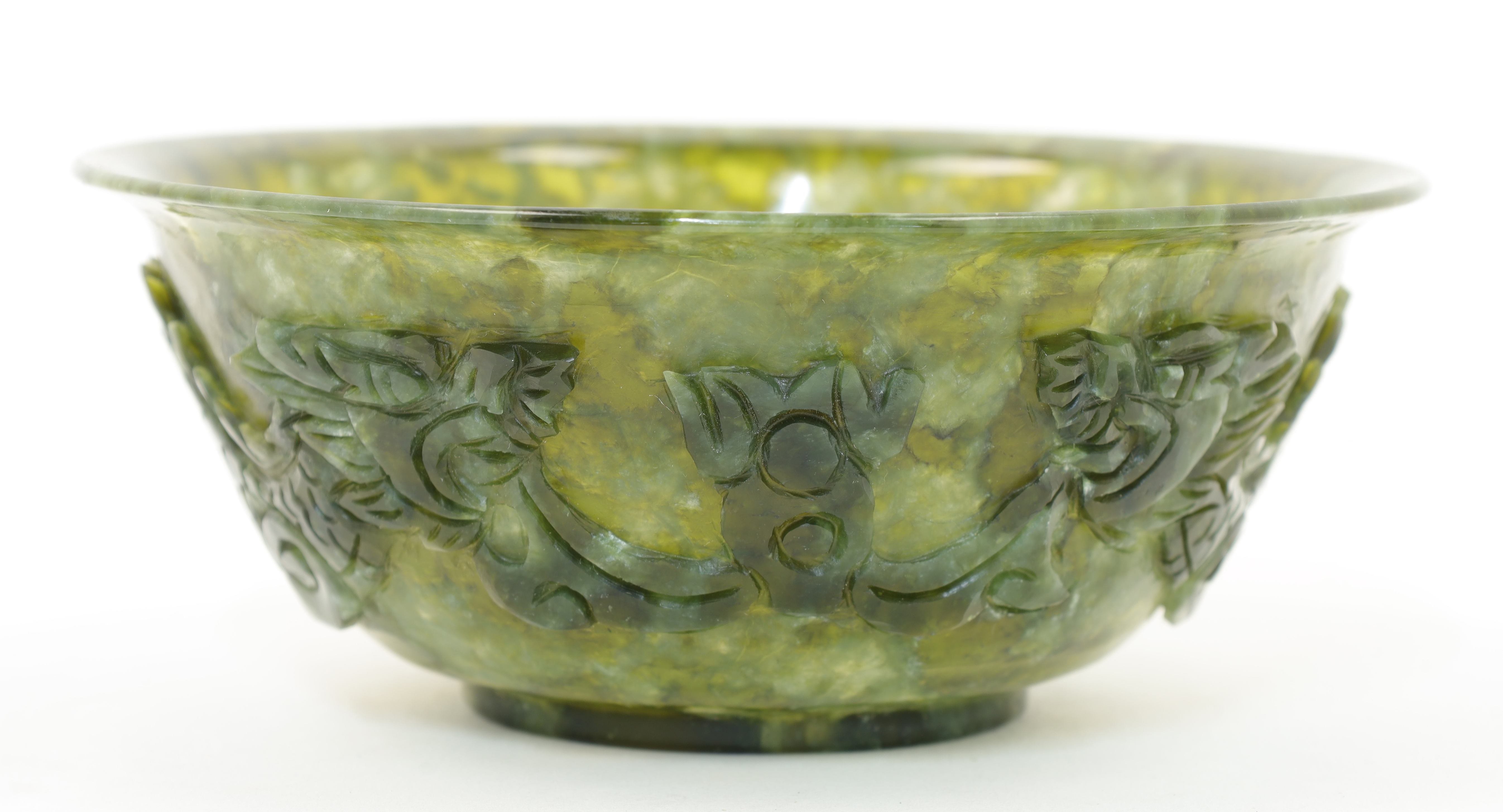 A Chinese spinach jade bowl, 20th century, with everted rim and short foot, the exterior carved w...