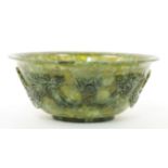 A Chinese spinach jade bowl, 20th century, with everted rim and short foot, the exterior carved w...