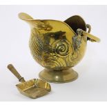 A late Victorian brass helmet shape coal scuttle, decorated with embossed fruits and scrolls, wit...