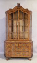 A Dutch walnut bookcase, first quarter 20th century, the glazed top above three drawers, on ball ...