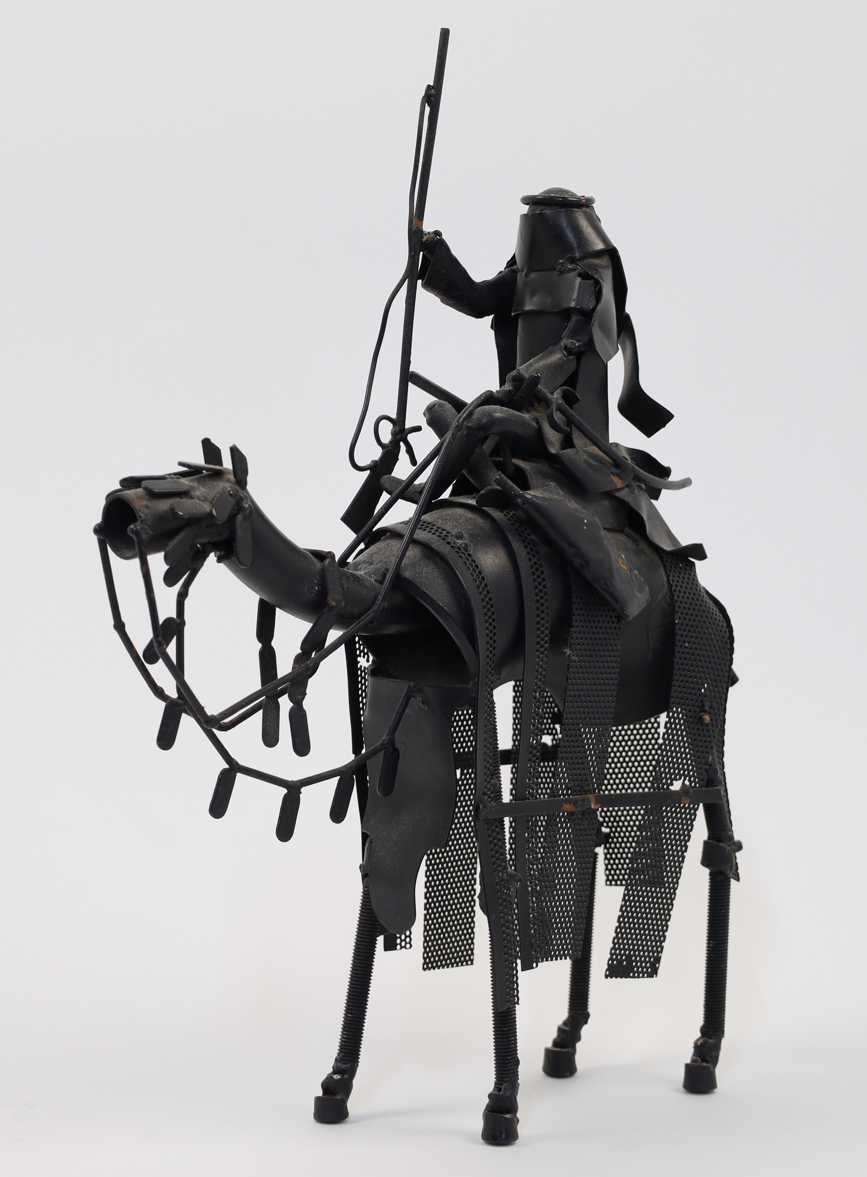 A metal sculpture of an Arab soldier with rifle riding a camel, 20th century, black painted tubul...