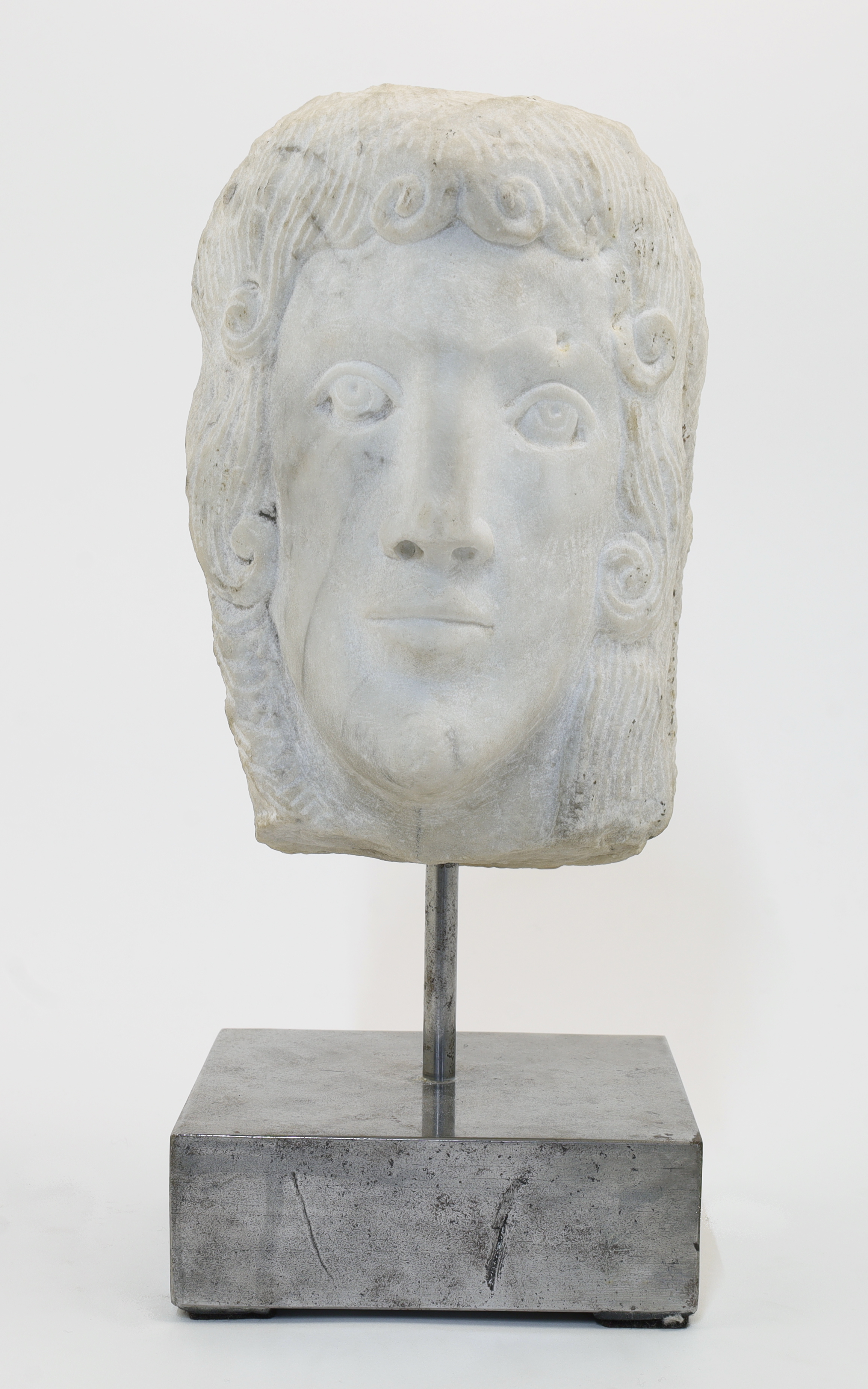 An Art Deco style carved marble head of a young male, 20th century, with long curling hair, on a ...