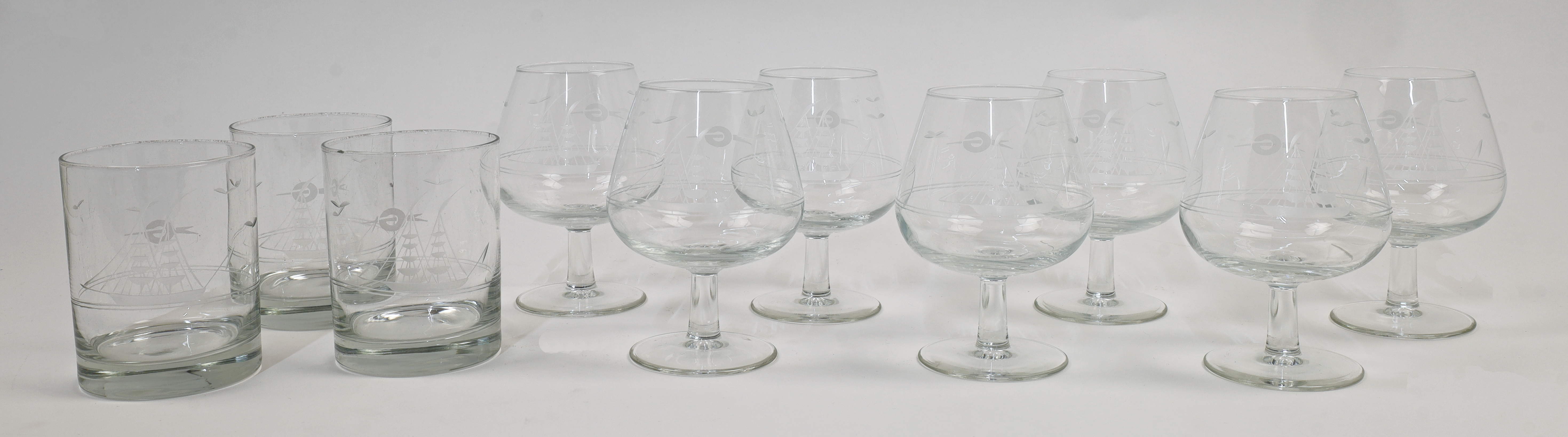 A set of seven French engraved brandy glasses, 20th century, each with stylised decoration of a t...