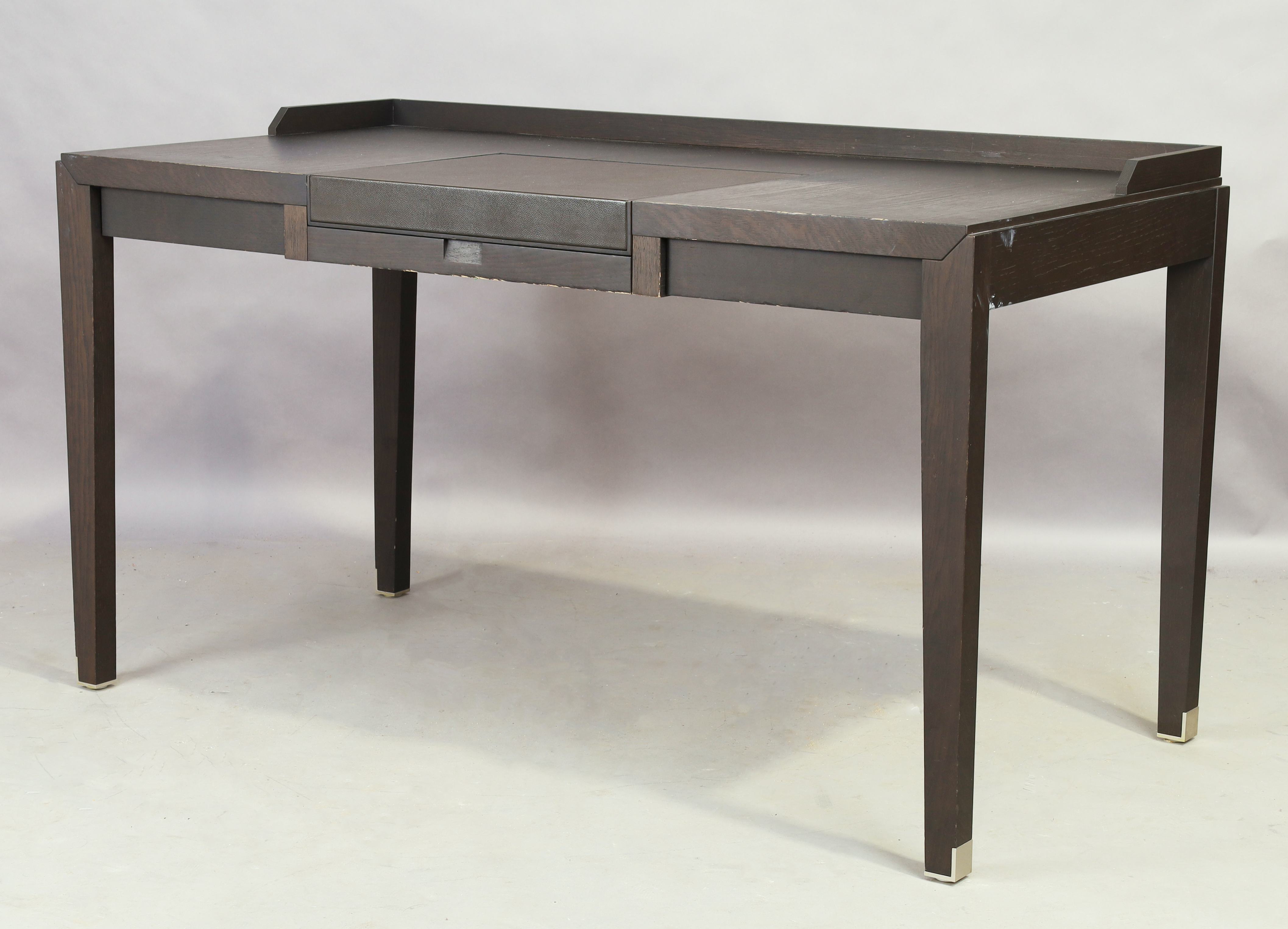 A contemporary ebonised desk, with hinged leather writing surface, revealing compartment, over si...