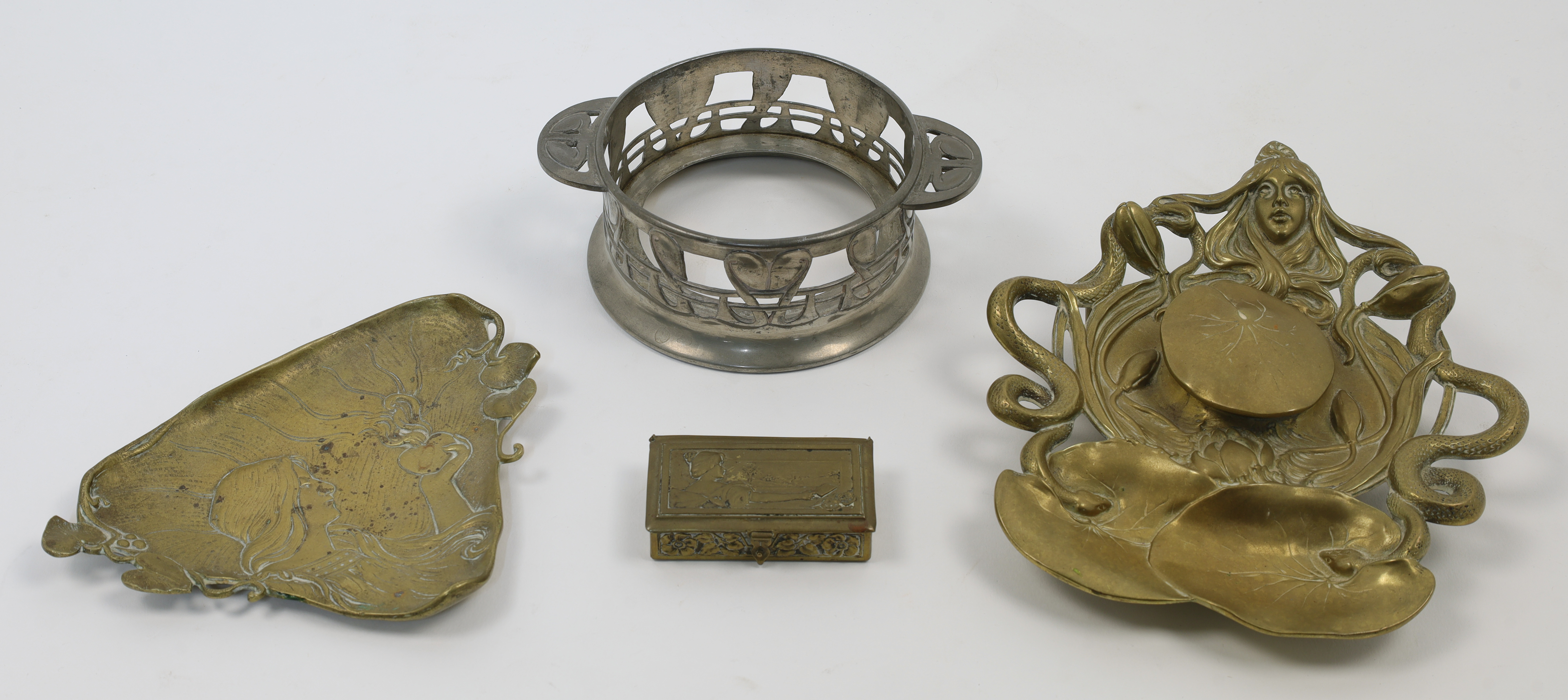 A group of Art Nouveau metalwares, comprising a brass inkwell with maiden's head and lily pads ma...