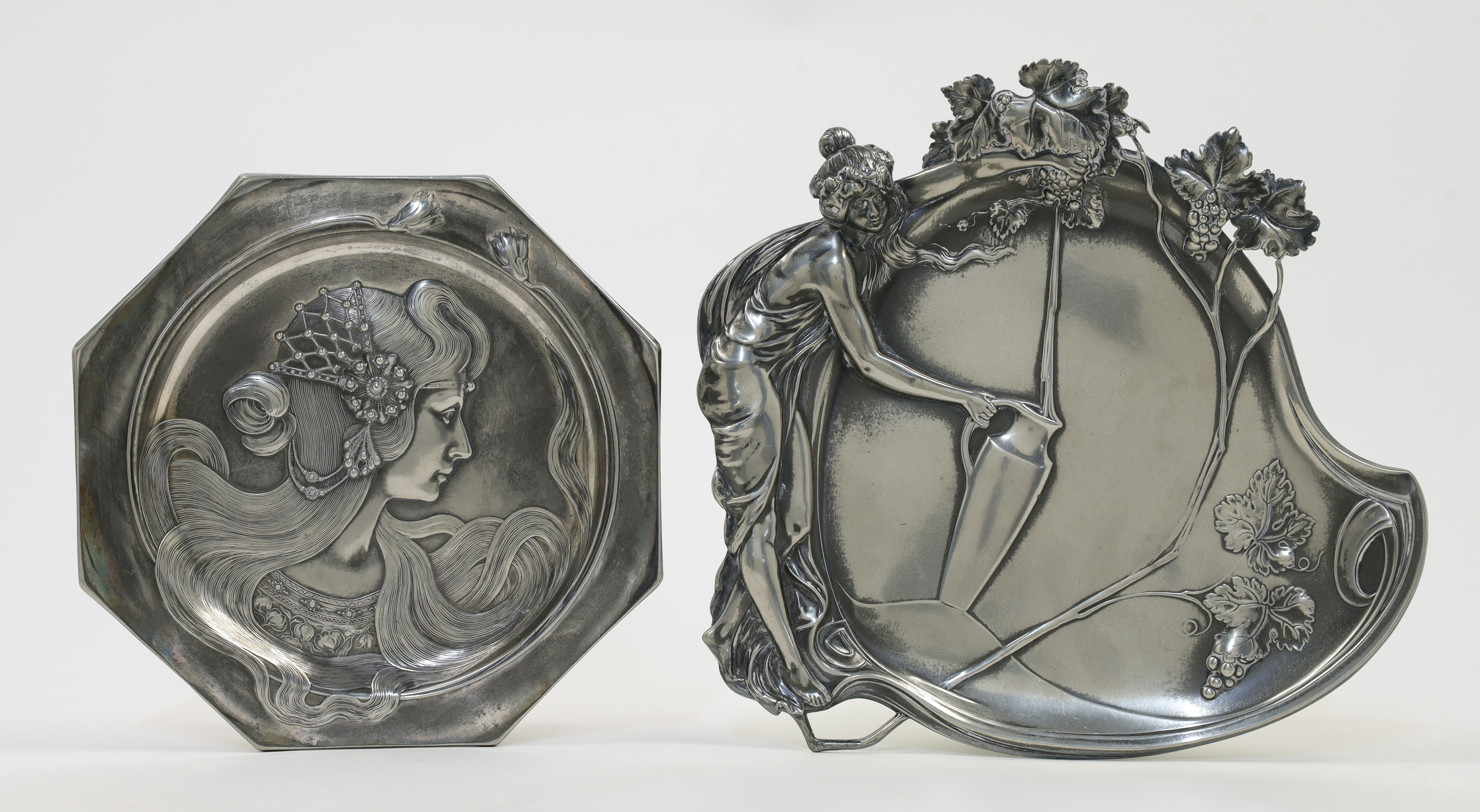 Two WMF pewter plates, early 20th century, comprising a hanging plate depicting a maiden filling ...