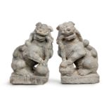 A pair of Chinese limestone figures of lions Late Qing dynasty Carved seated on square stands a...