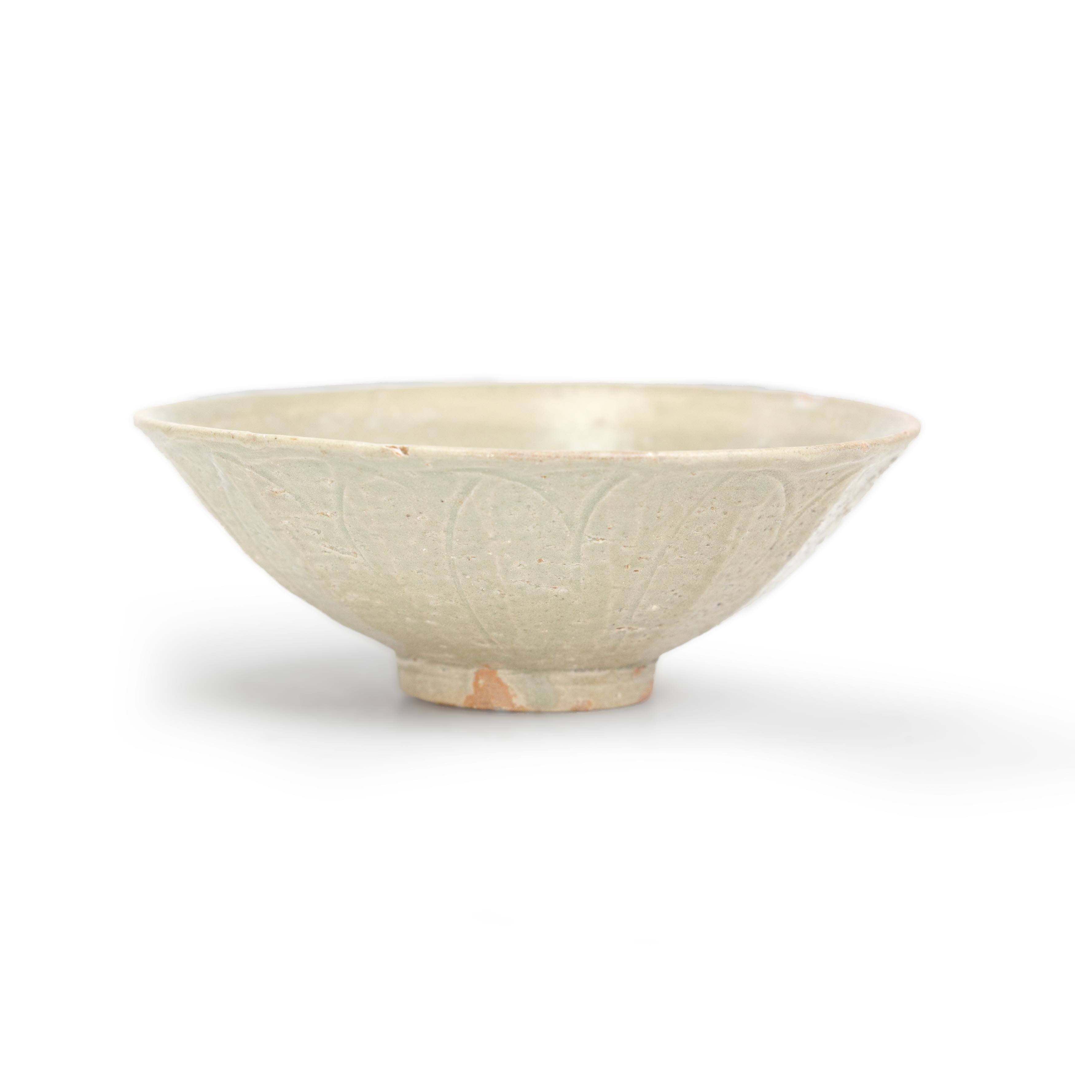 A Chinese celadon-glazed carved lotus bowl Song / Yuan dynasty carved to the exterior with lotu...