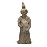 A Chinese pottery figure of a court lady Tang dynasty Modelled standing clutching part of her r...