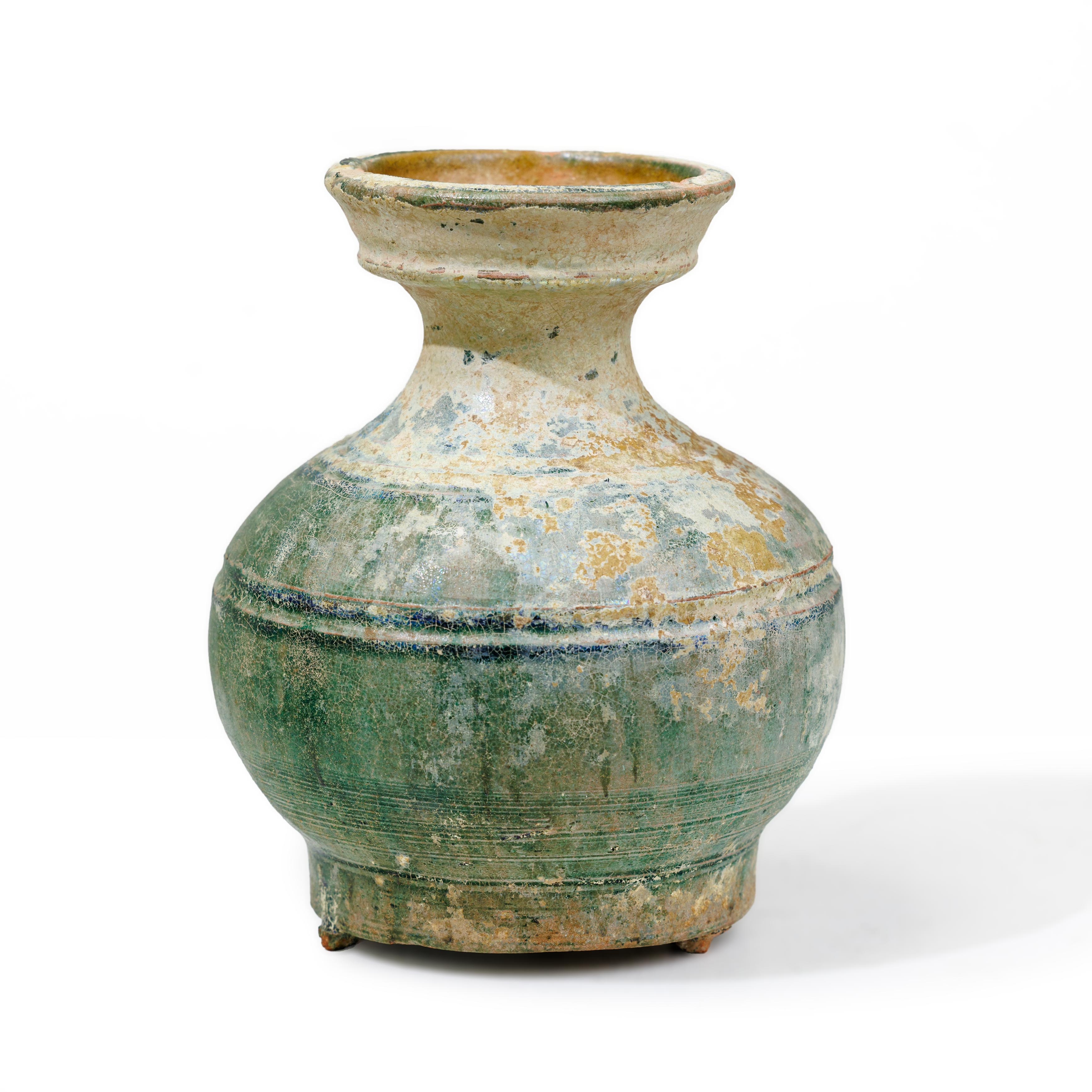 A Chinese green glazed jar, hu Han dynasty With flared mouth above bands of circles incised to ...