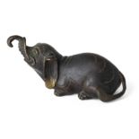 A Chinese bronze 'elephant' paper weight Ming dynasty The recumbent beast raising his head and ...