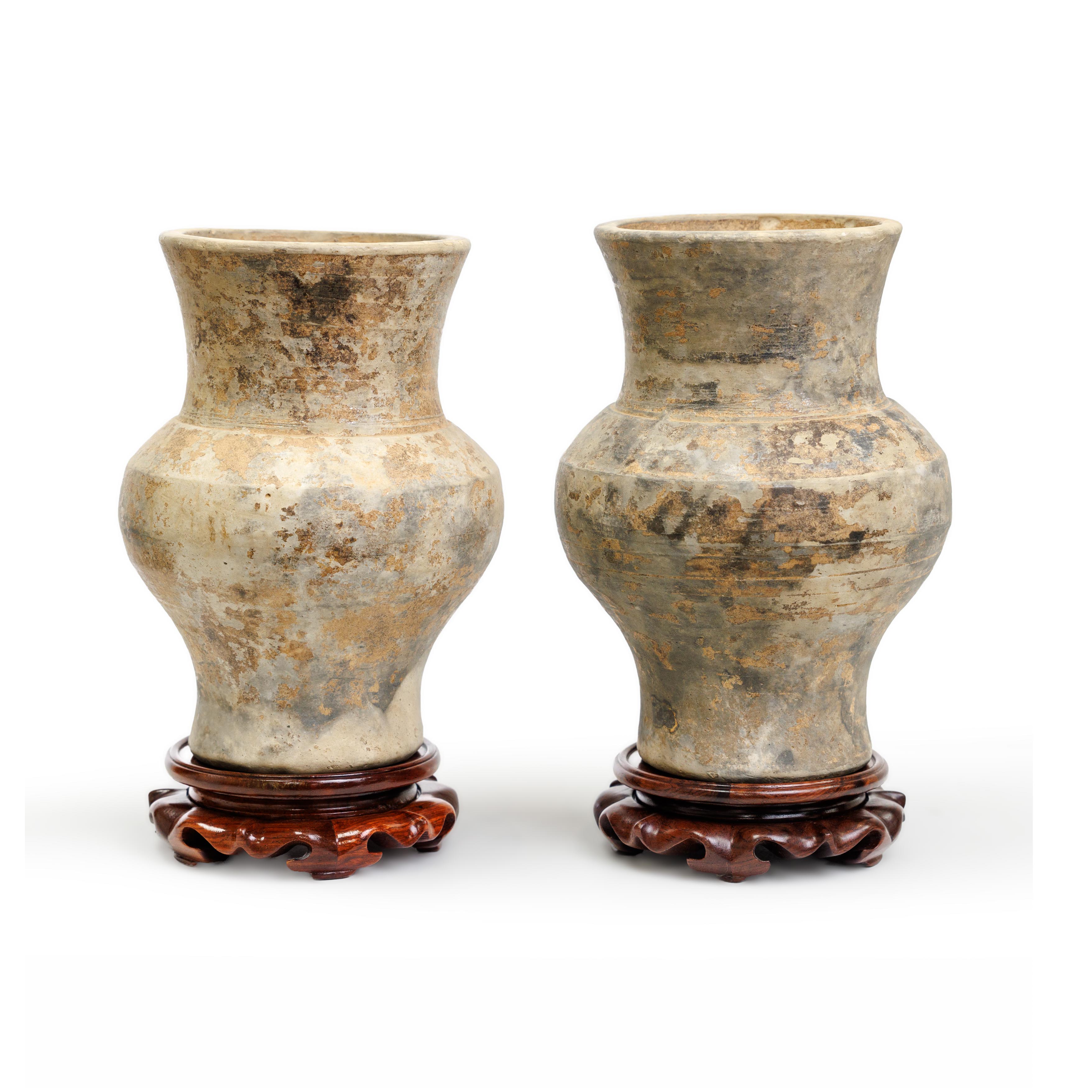 A pair of Chinese painted earthenware jars, hu Han dynasty Each raised on spreading foot with f...
