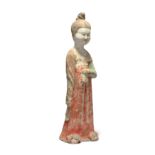 A Chinese pottery figure of a court lady  Tang dynasty Modelled standing with her right arm by ...